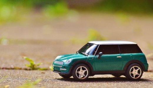 green scale model car on brown pavement